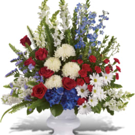 Red roses, white flowers, and blue blooms in a white vase