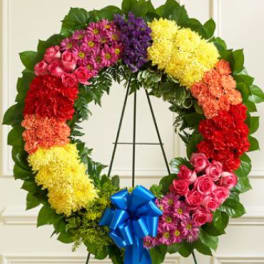 Large colorful floral wreath on a stand with a blue bow