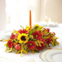 Low floral centerpiece with sunflowers and red daisies on a table