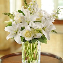 White lilies and roses arranged in a clear glass vase