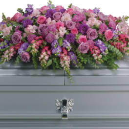 Pink and purple floral casket spray on a gray casket
