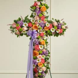 Cross-shaped floral standing spray with multicolored flowers and a purple ribbon