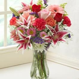 Mixed bouquet of pink and red flowers in a clear glass vase