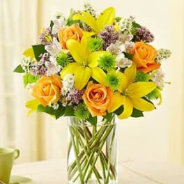 Bouquet of yellow lilies and orange roses in a clear glass vase