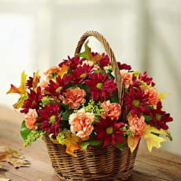 Basket of red and peach flowers with autumn leaves