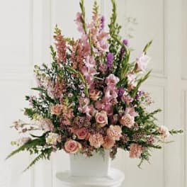 Tall pink floral arrangement in a white container