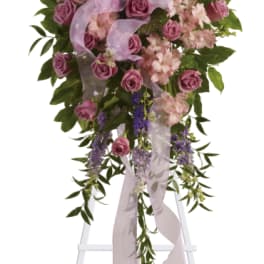 Standing floral spray with pink roses and lavender ribbon on an easel