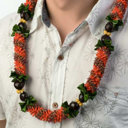 Orange and green floral lei with dark beads worn over a light patterned shirt