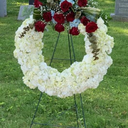 Standing funeral wreath with white flowers and red roses on an easel