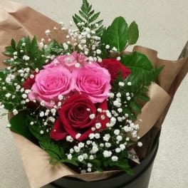 Bouquet of pink and red roses with baby's breath in brown paper