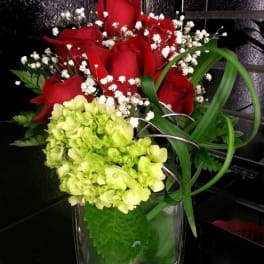 Red roses and green hydrangea in a clear glass vase