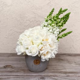 White floral arrangement in a gray vase with green spikes