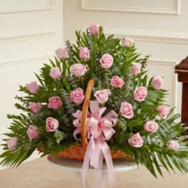 Basket arrangement of pink roses with a pink ribbon bow