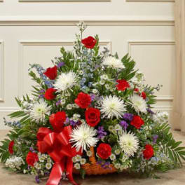 Large basket arrangement of red roses, white spider mums, and purple flowers with a red ribbon