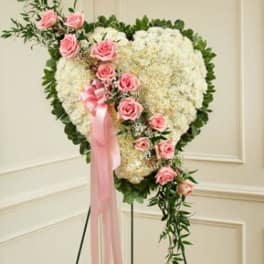 Heart-shaped floral wreath with pink roses and a pink ribbon