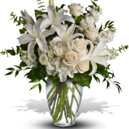 White lilies and cream roses in a clear glass vase