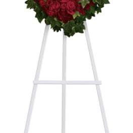 Heart-shaped red rose wreath on a white easel