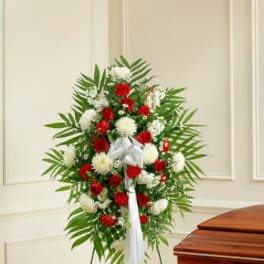 Standing floral spray with red and white flowers on a white ribboned easel
