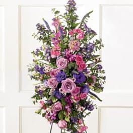 Tall standing spray of pink and purple flowers on a black easel