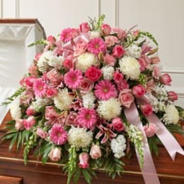 Large pink and white funeral spray with ribbon on a casket