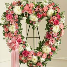 Heart-shaped floral wreath with pink and white flowers on a stand