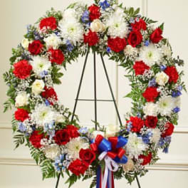 Large red, white, and blue floral wreath on a stand with ribbon