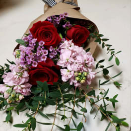 Bouquet of red roses and pink flowers wrapped in brown paper