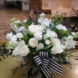 White floral arrangement with a striped ribbon in a low container