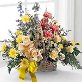 Basket arrangement of roses, daisies, and mixed flowers with a yellow ribbon