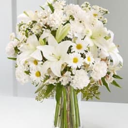 White lilies and daisies arranged in a clear glass vase