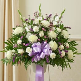 White and purple floral standing spray with a lavender ribbon bow