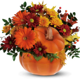Pumpkin-shaped vase with orange and red flowers and autumn leaves