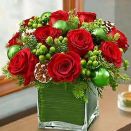 Red roses arranged in a square glass vase with green accents