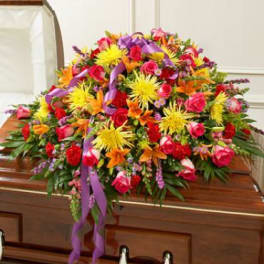 Large colorful floral spray on a casket with purple ribbon