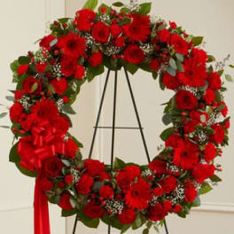 Red floral wreath on a black stand with a red ribbon