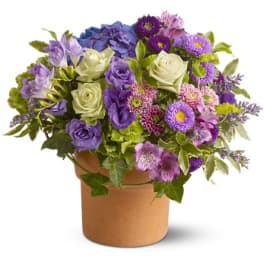 Purple and white mixed flower arrangement in a brown vase