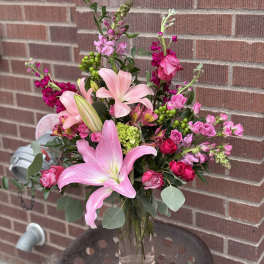 Pink lilies and mixed pink flowers in a clear glass vase