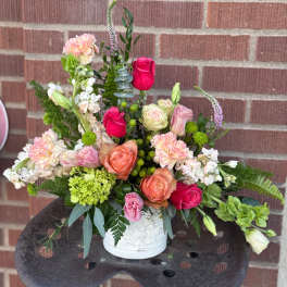 Mixed bouquet of pink, peach, and white flowers in a white vase