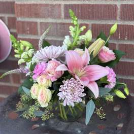 Pink lilies and pastel roses in a glass vase