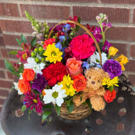 Colorful mixed flower basket with a teddy bear