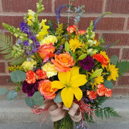 Colorful mixed bouquet in a glass vase with roses and lilies
