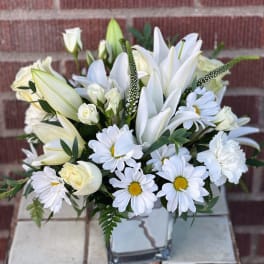 White lilies and daisies arranged in a clear glass vase