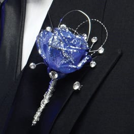 Blue rose boutonniere with rhinestone accents on a suit lapel