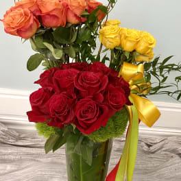 Three rose bouquets in a glass vase with yellow ribbon