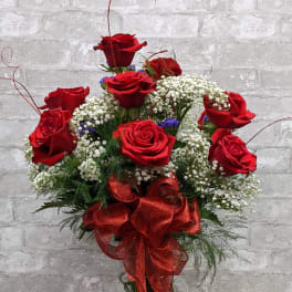 Red roses arranged in a clear glass vase with a red ribbon bow
