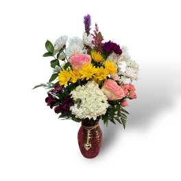 Mixed bouquet in a pink vase with pink, yellow, white, and purple flowers