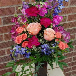 Tall mixed bouquet with pink roses and purple-blue flowers in a black vase