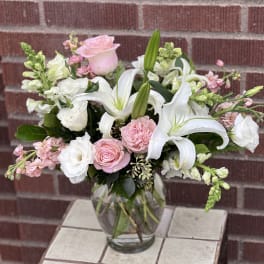 Pink roses and white lilies arranged in a clear glass vase