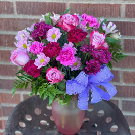 Pink and purple mixed bouquet in a frosted vase with a lavender bow