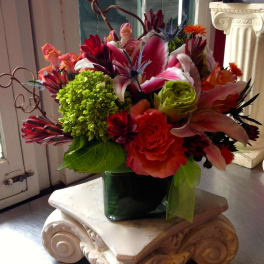 Colorful mixed flower arrangement in a dark green vase